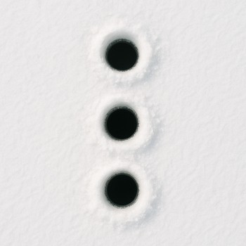 Top-down view of three drilled ice holes arranged in a small grid pattern