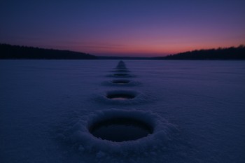 Row of ice fishing holes stretching across a ridge at dusk
