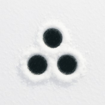 Top-down view of three ice holes of different depths marked with small flags